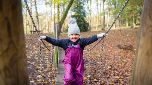 Child playing on a wooden bridge in the playground at Nostell